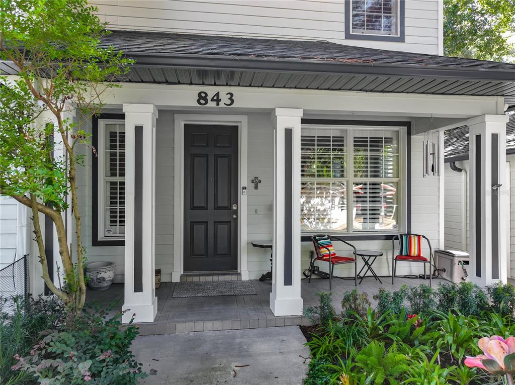 A covered front porch features a dark door, white columns, and two chairs with colorful cushions — 843 ALTALOMA AVENUE, ORLANDO, FL