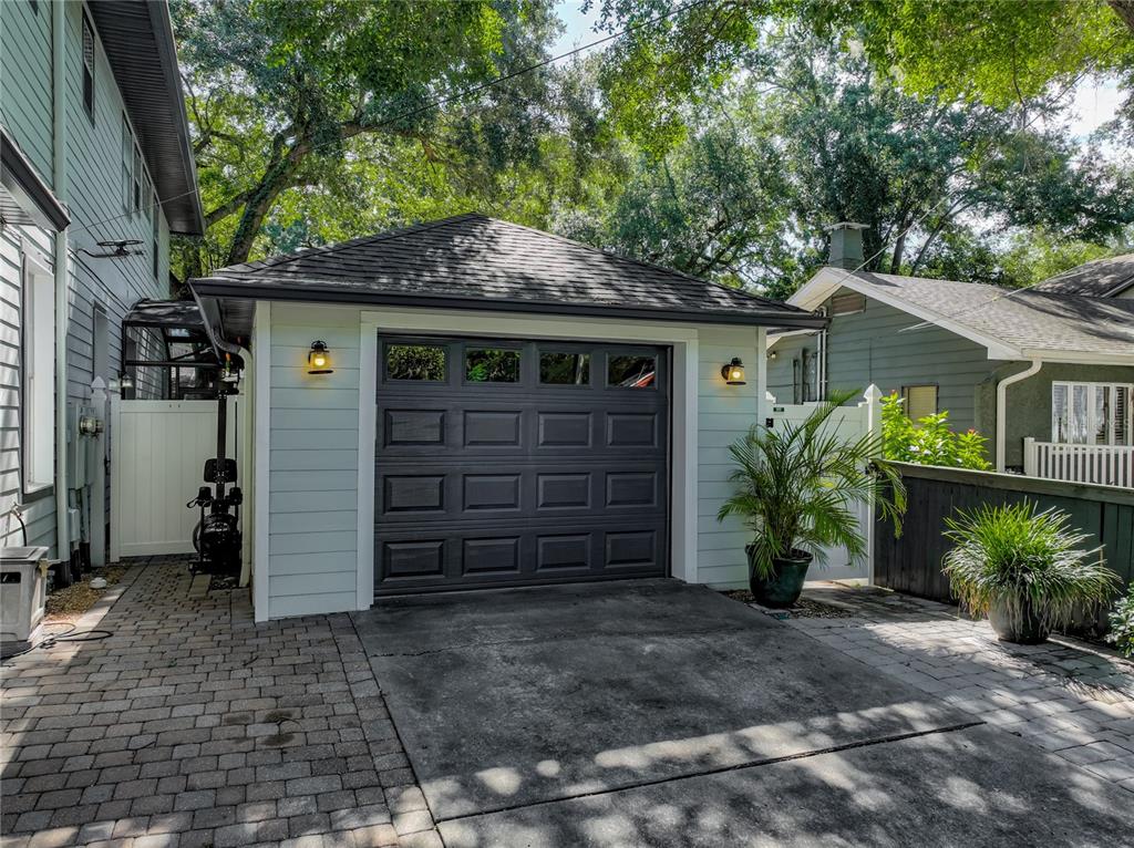 A detached garage with a dark door, light siding, and a paved driveway — 843 ALTALOMA AVENUE, ORLANDO, FL