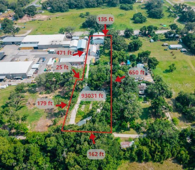 An aerial view shows a commercial warehouse complex adjacent to a wooded residential property — 3350 4TH STREET, OKAHUMPKA, FL