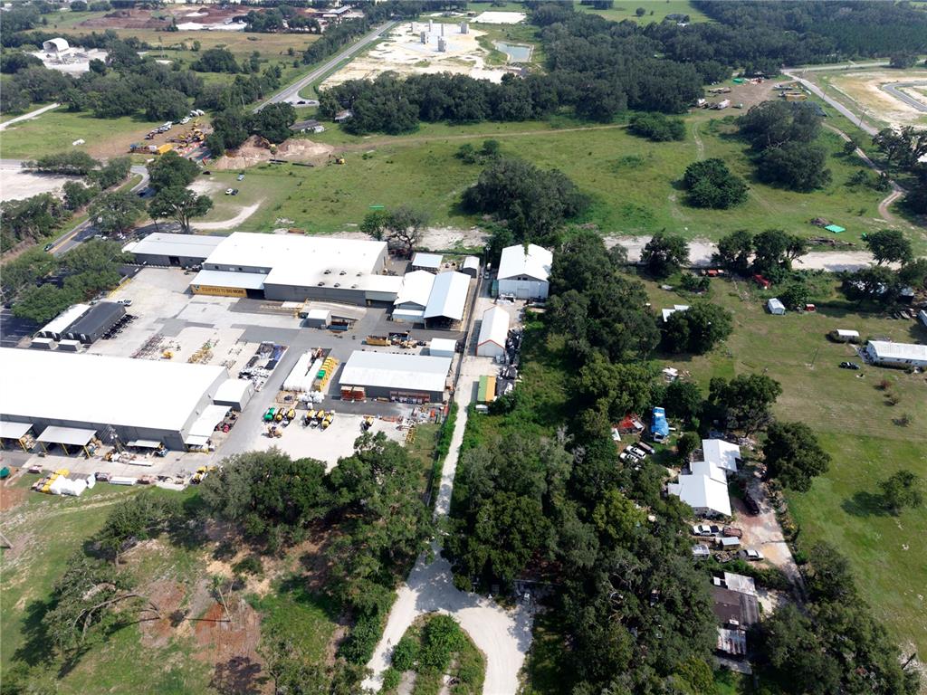 An aerial view shows a rural property with industrial buildings, residential structures, and wooded areas — 3350 4TH STREET, OKAHUMPKA, FL