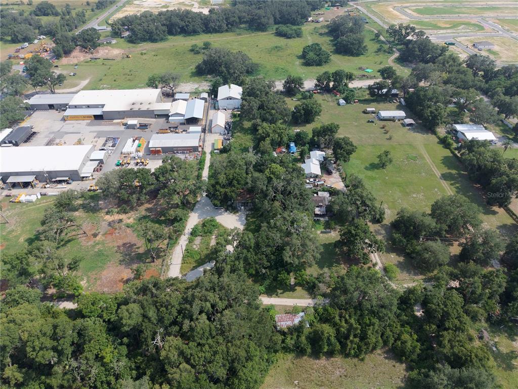 An aerial view shows a large industrial complex adjacent to a wooded residential property — 3350 4TH STREET, OKAHUMPKA, FL