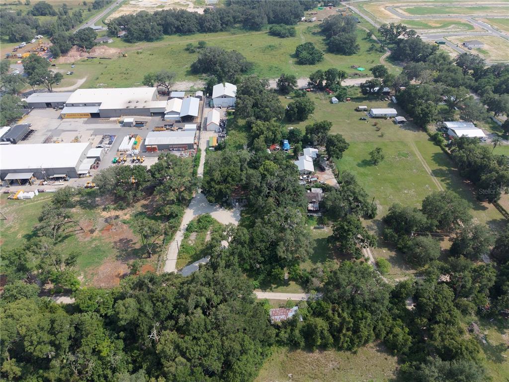 An aerial view shows a large industrial complex adjacent to a wooded residential property — 3350 4TH STREET, OKAHUMPKA, FL