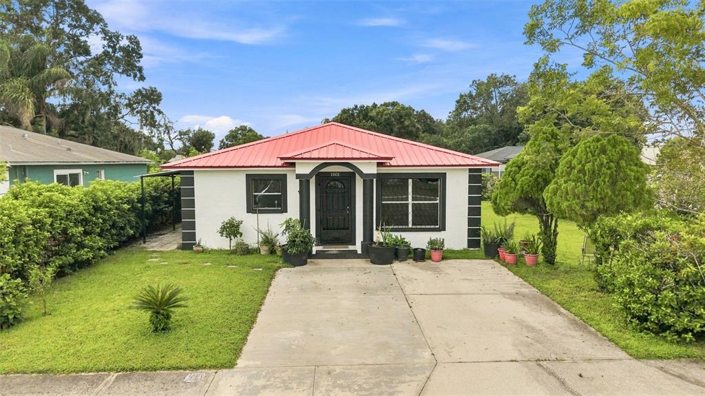 A single-story house with a red metal roof, white stucco walls, and a concrete driveway — 1801 BETHUNE DRIVE, PLANT CITY, FL