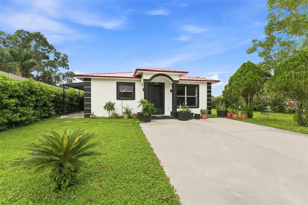 A single-story white house with a red metal roof and black trim features a concrete driveway — 1801 BETHUNE DRIVE, PLANT CITY, FL