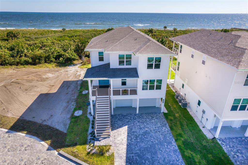 An elevated white coastal home with a paved driveway sits near the ocean — 204 SURFVIEW LANE, PALM COAST, FL