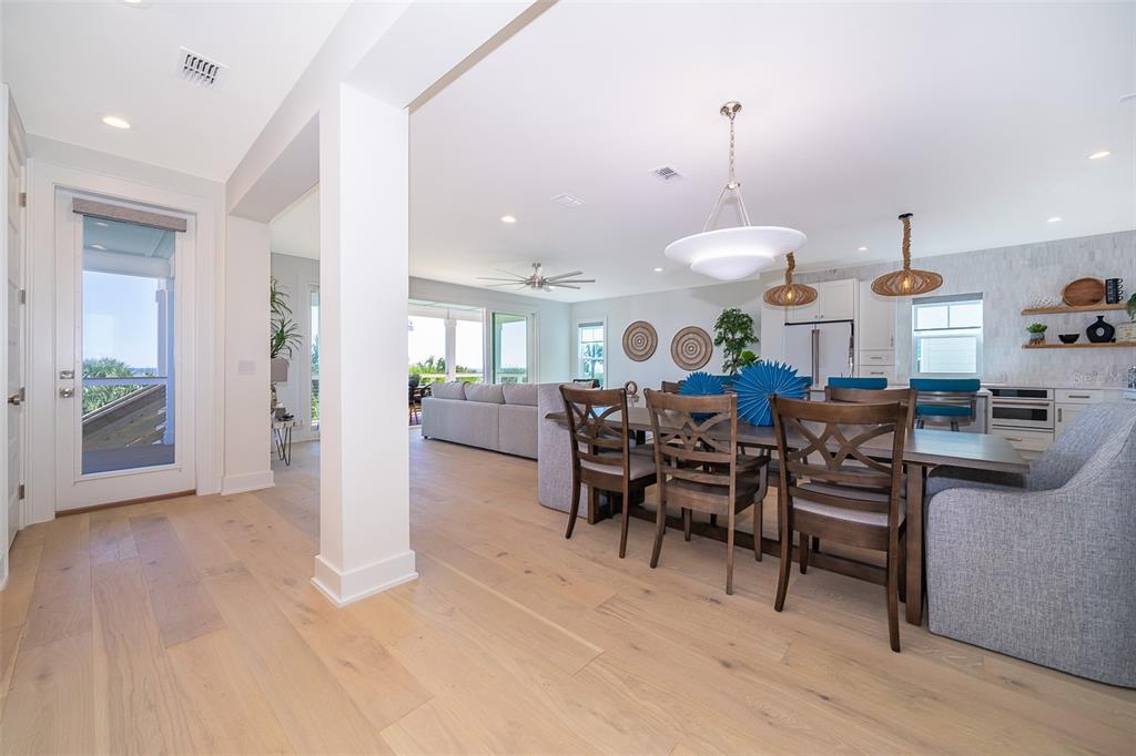 An open-concept living and dining area features light wood floors, modern lighting, and neutral furniture — 204 SURFVIEW LANE, PALM COAST, FL