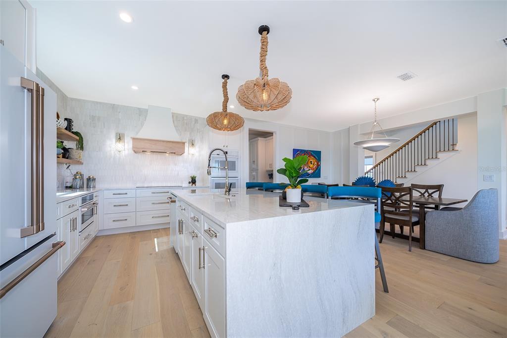 A modern kitchen features a large white stone island, light wood floors, and two pendant lights — 204 SURFVIEW LANE, PALM COAST, FL
