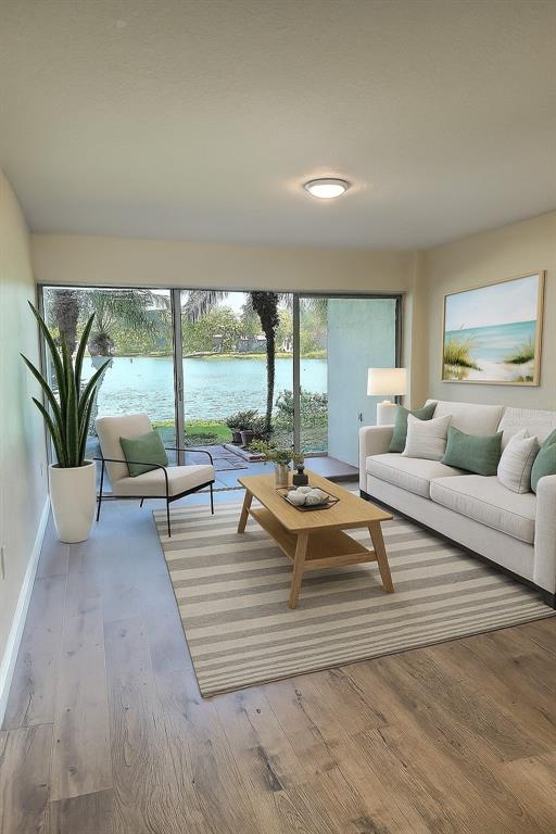 A living room features a sofa, accent chair, coffee table, and sliding doors overlooking a lake — 620 ORANGE DRIVE UNIT 225, ALTAMONTE SPRINGS, FL