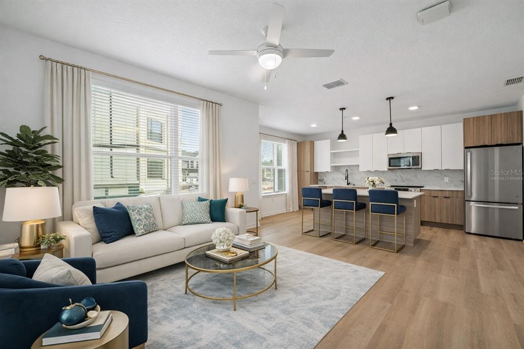 An open-concept living room and kitchen featuring a sofa, island with stools, and wood flooring — 2285 CROWN VILLAGE ROAD UNIT TH1, OCOEE, FL