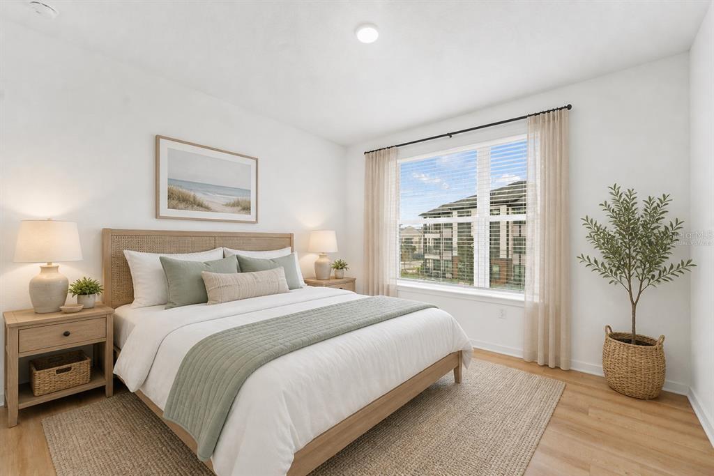 A bedroom features a bed with a rattan headboard, light wood floors, and a large window — 2285 CROWN VILLAGE ROAD UNIT TH1, OCOEE, FL
