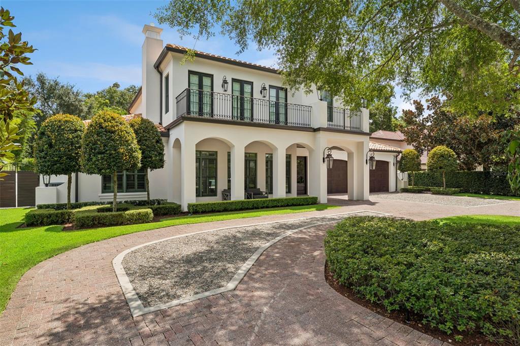 A two-story Mediterranean-style house with a brick driveway, arched entryways, and a second-floor balcony — 276 DETMAR DRIVE, WINTER PARK, FL