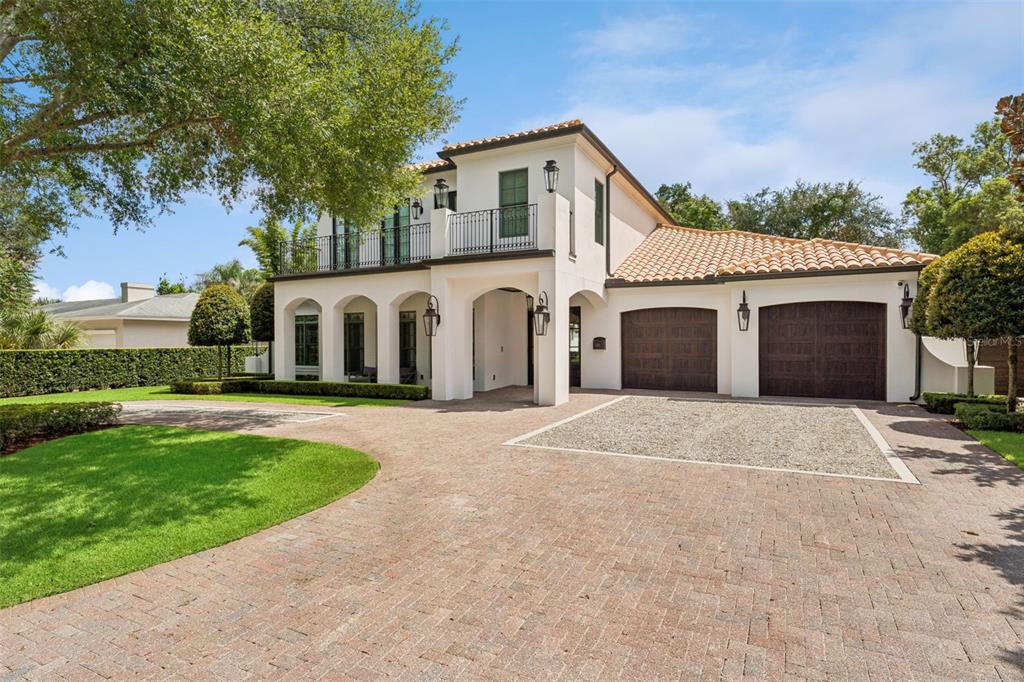 A two-story Mediterranean-style house with a brick driveway, a gravel parking area, and a garage — 276 DETMAR DRIVE, WINTER PARK, FL