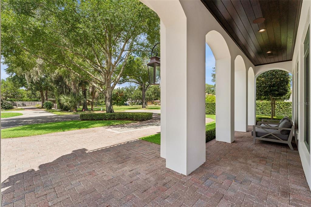A covered brick patio features white arched columns and a dark wood-paneled ceiling — 276 DETMAR DRIVE, WINTER PARK, FL