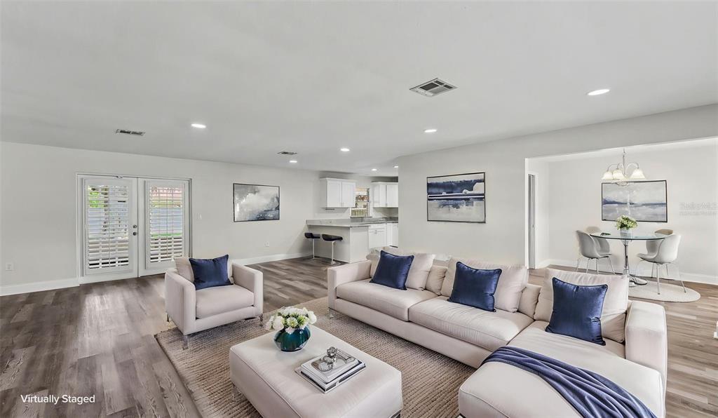 A living room with light wood floors, a sectional sofa, and an open kitchen area — 4520 OLD COLONY ROAD, MULBERRY, FL