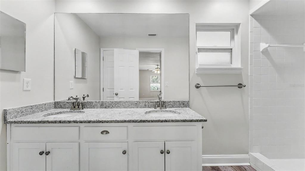 A bathroom features a double vanity with a granite countertop, white cabinets, and a tiled shower — 4520 OLD COLONY ROAD, MULBERRY, FL