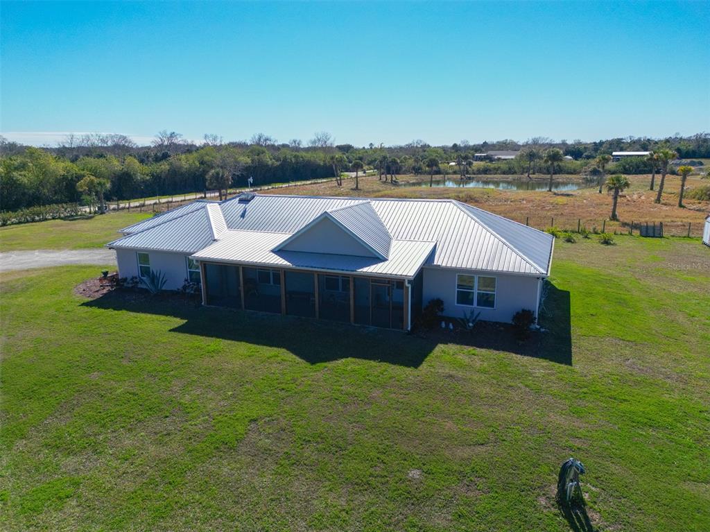 An aerial view of a single-story house with a metal roof and a screened-in porch — 3440 HAMMOCK ROAD, MIMS, FL