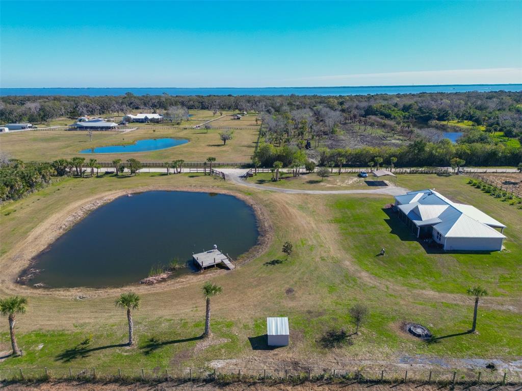 An aerial view shows a house with a metal roof, a pond, and surrounding acreage — 3440 HAMMOCK ROAD, MIMS, FL
