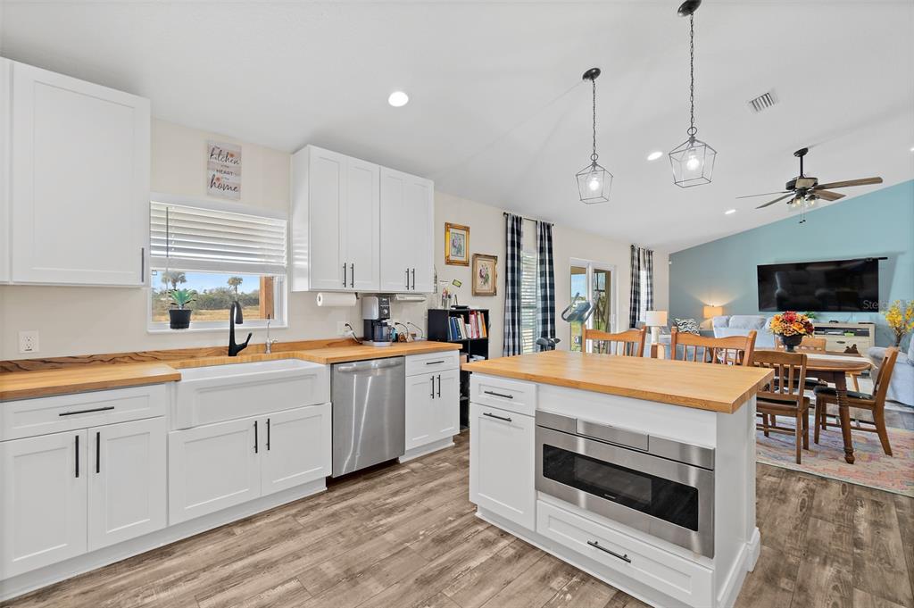 A kitchen with white cabinets, butcher block countertops, and a stainless steel microwave island — 3440 HAMMOCK ROAD, MIMS, FL