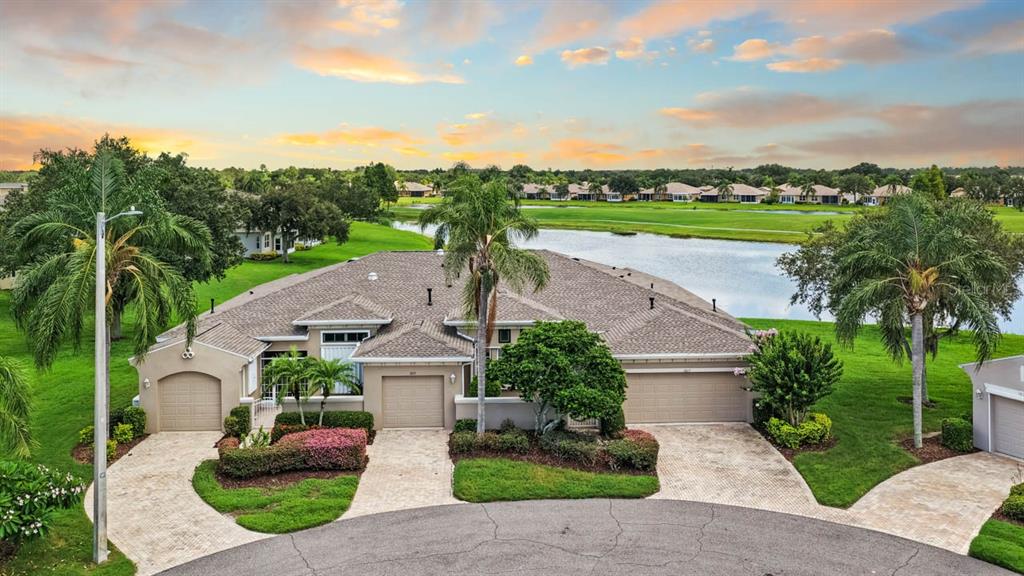 An aerial view of a multi-unit residential building with garages, palm trees, and a lake — 1015 CHELSEA GREENS COURT UNIT 40, SUN CITY CENTER, FL