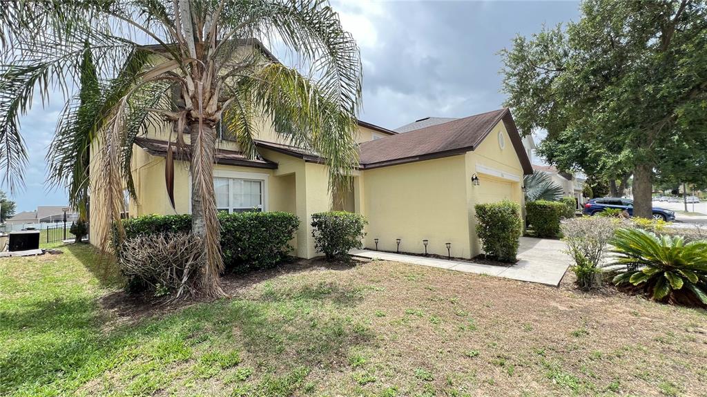 A two-story yellow house with a palm tree and a paved driveway in front — 216 VERDI STREET, DAVENPORT, FL