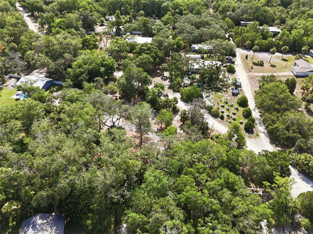 An aerial view shows a wooded residential lot with several houses and a dirt road — JEBERT DRIVE, ARIPEKA, FL