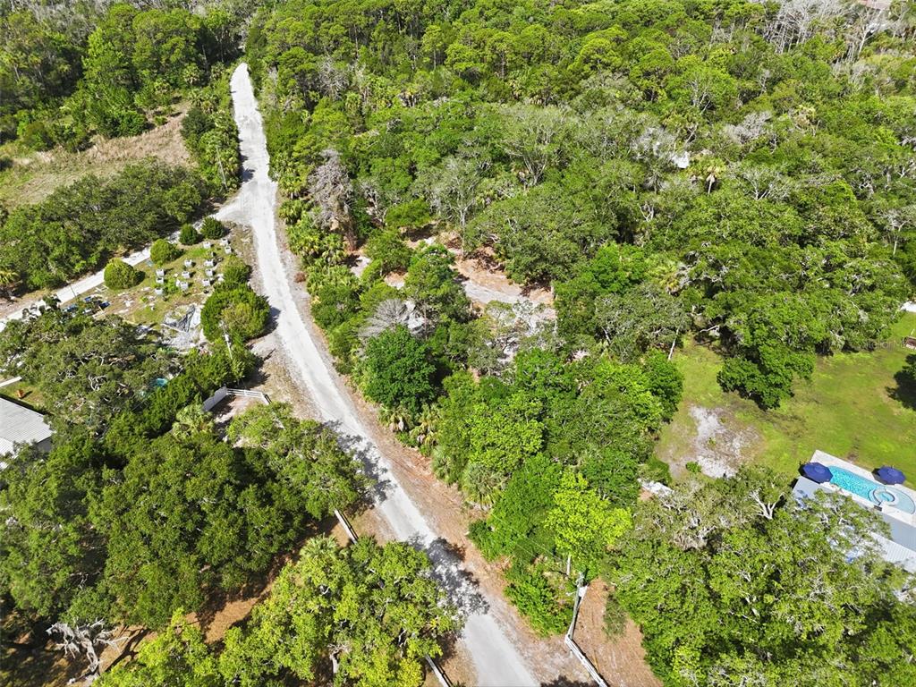 An aerial view shows a narrow paved road winding through a dense, wooded residential area — JEBERT DRIVE, ARIPEKA, FL