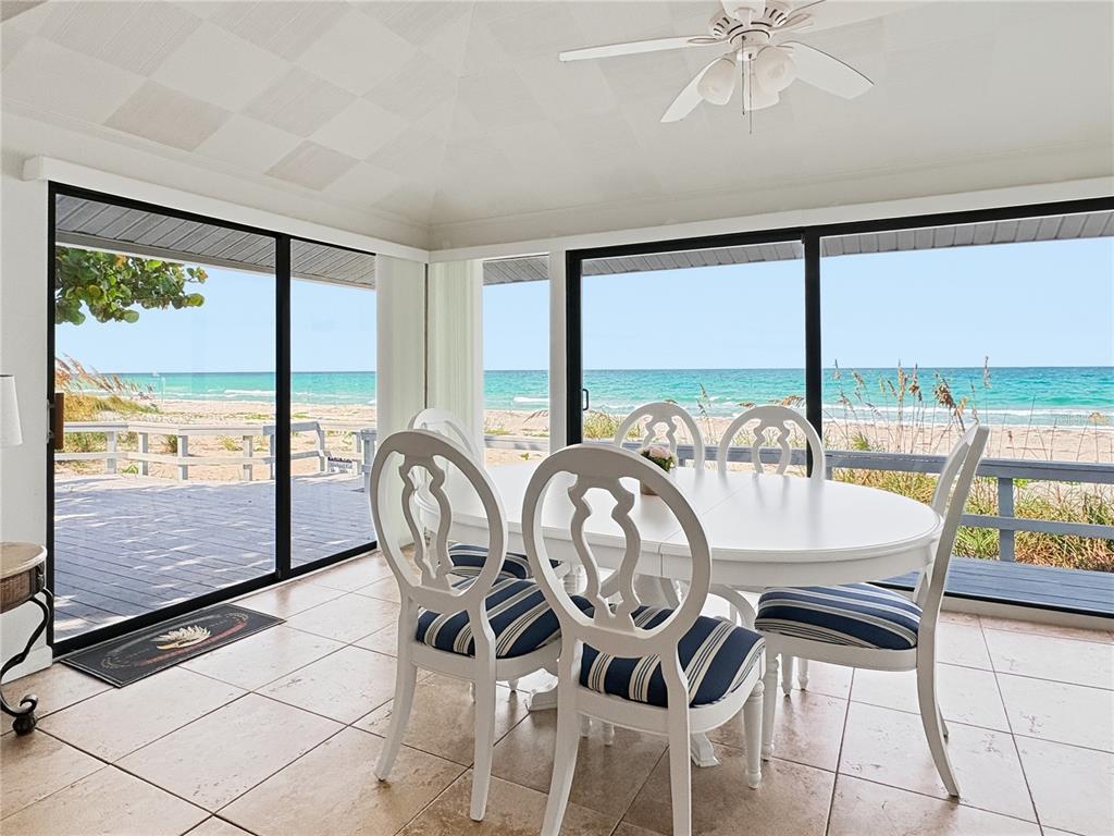 A patio with outdoor furniture overlooks a sandy beach and the ocean under a tree — 2823 GULF OF MEXICO DRIVE, LONGBOAT KEY, FL