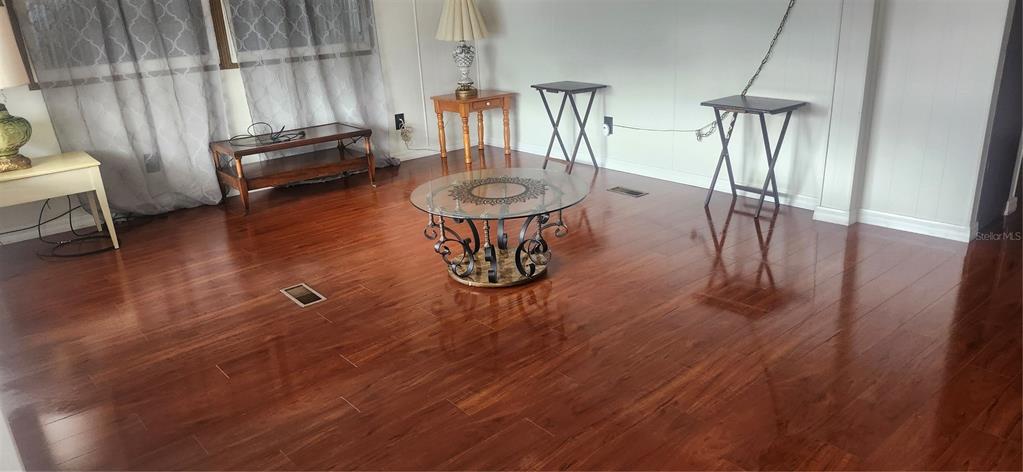 A living room features hardwood flooring, a glass-topped coffee table, and several small side tables — 3229 TIKI DRIVE, HOLIDAY, FL