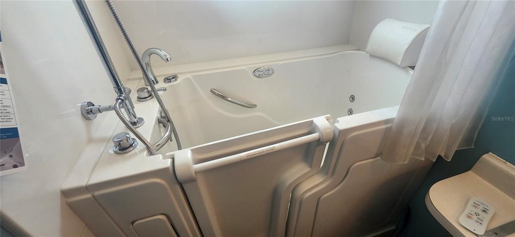 A white walk-in bathtub with a handheld showerhead and a built-in headrest is shown — 3229 TIKI DRIVE, HOLIDAY, FL