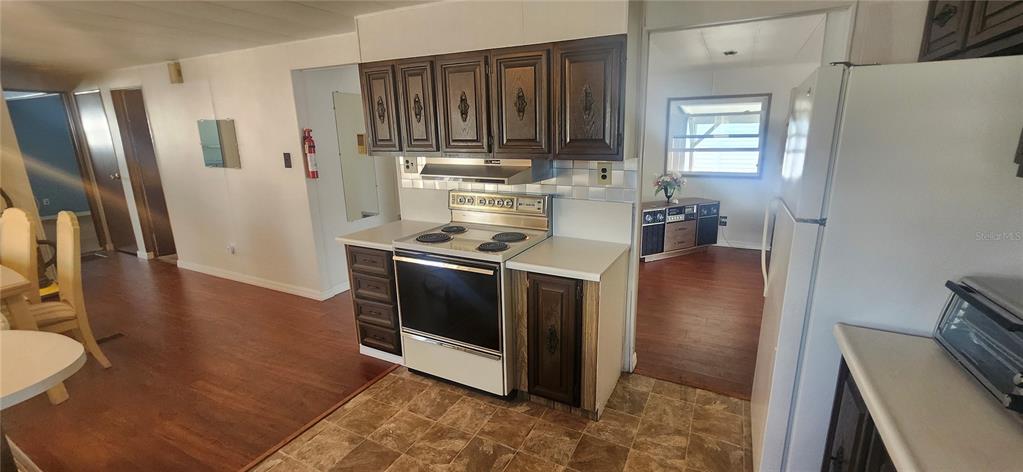 A kitchen with dark wood cabinets, a white stove, and light-colored countertops — 3229 TIKI DRIVE, HOLIDAY, FL