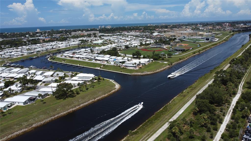 An aerial view shows a canal with two boats, a residential community, and a baseball field — 602 CAREFREE, VENICE, FL
