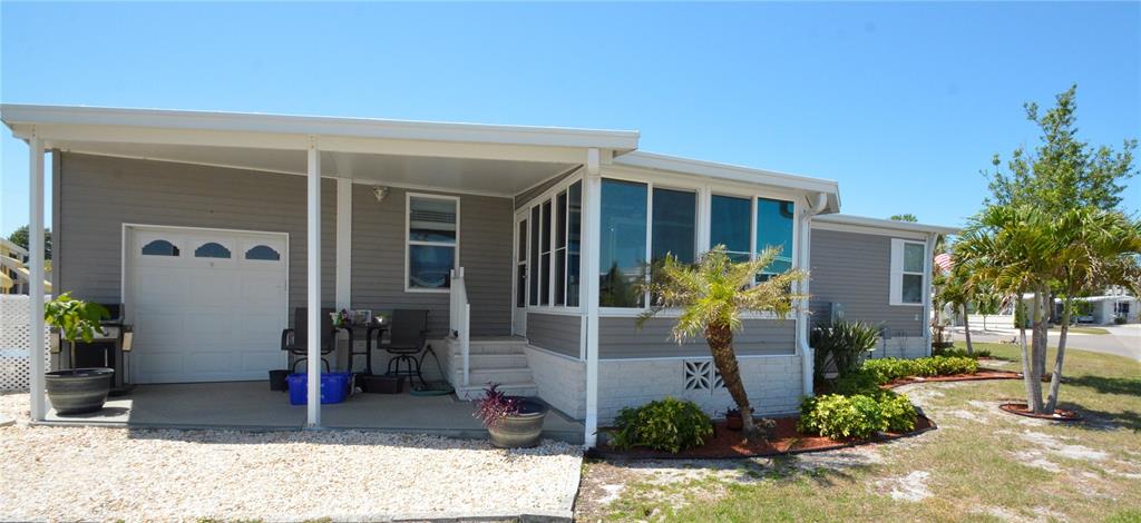 A single-story manufactured home features a covered patio, a garage door, and a sunroom — 602 CAREFREE, VENICE, FL