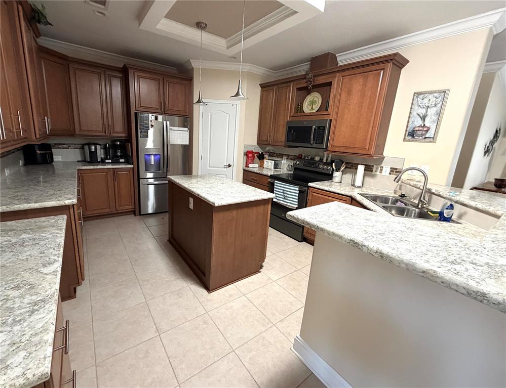 A kitchen features wood cabinets, granite countertops, a center island, and stainless steel appliances — 602 CAREFREE, VENICE, FL