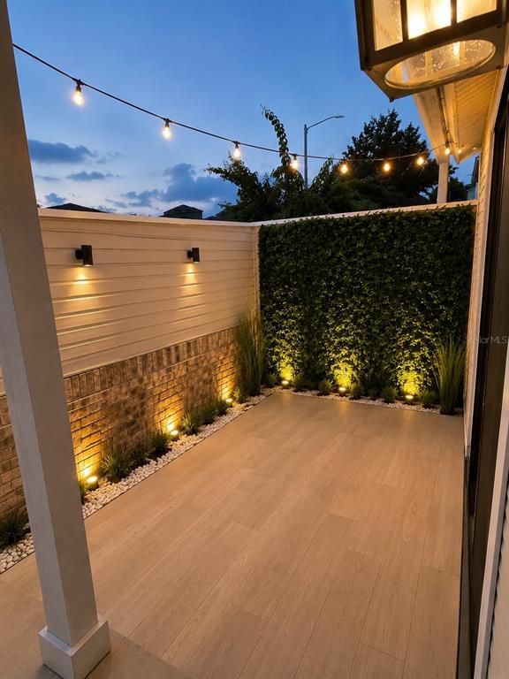 A small outdoor patio features wood-look tile flooring, a brick and siding wall, and string lights — 3111 RIO GRANDE TRAIL, KISSIMMEE, FL