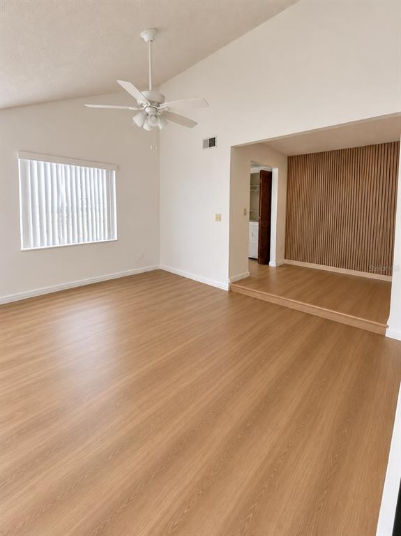 A living room with light wood-look flooring, a ceiling fan, and a raised wood-paneled alcove — 3111 RIO GRANDE TRAIL, KISSIMMEE, FL