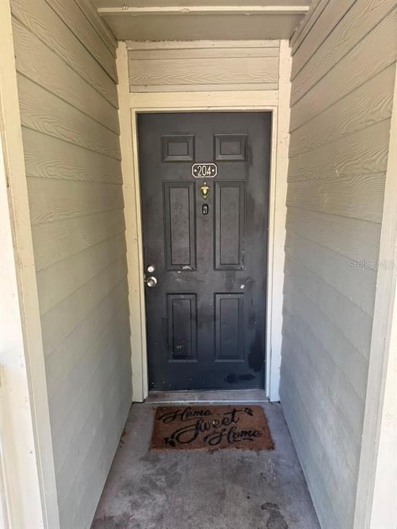 A hallway with light-colored tile flooring features two white interior doors against beige walls — 5962 WESTGATE DRIVE UNIT 204, ORLANDO, FL