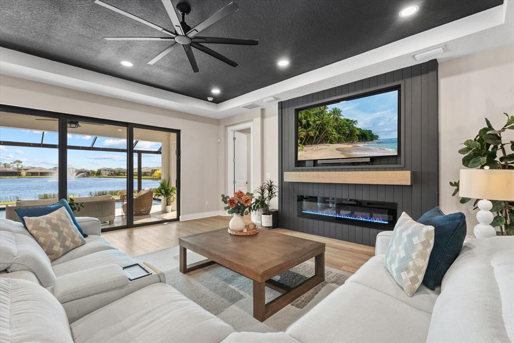 A living room features a dark ceiling, a fireplace with a television, and sliding glass doors — 12801 MORNING MIST PLACE, VENICE, FL