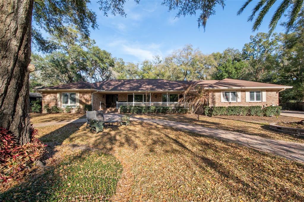A single-story brick house with a front porch, stone walkway, and mature trees — 2009 WOODY DRIVE, WINDERMERE, FL