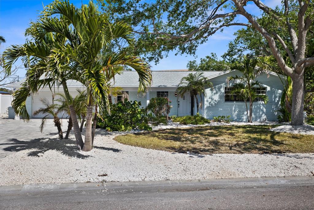 A single-story house with light blue siding, a white garage, and palm trees in the yard — 10001 S YACHT CLUB DRIVE, TREASURE ISLAND, FL