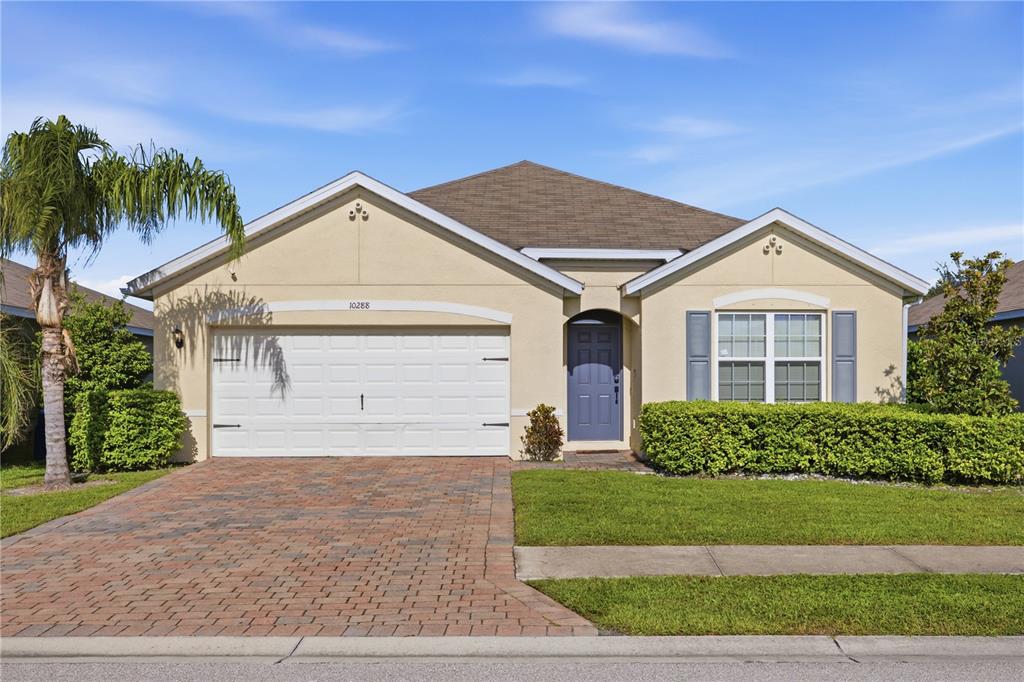 A single-story house with a beige stucco exterior, a two-car garage, and a paved driveway — 10288 SILVER POND LANE, LEHIGH ACRES, FL