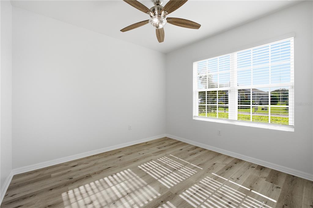 An empty bedroom features light wood-look flooring, white walls, a ceiling fan, and a window — 10288 SILVER POND LANE, LEHIGH ACRES, FL