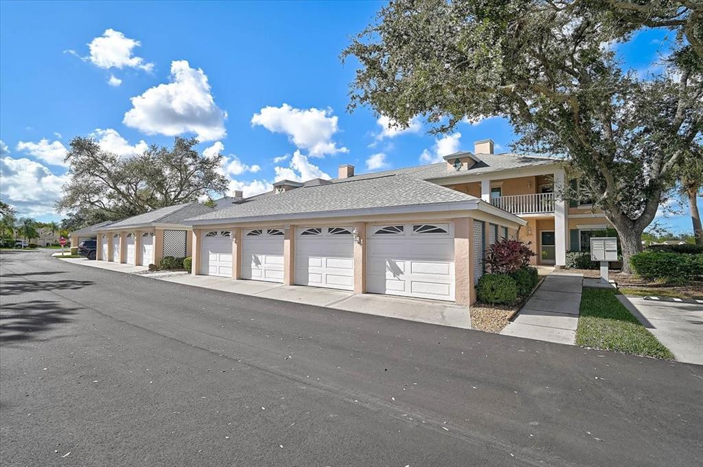 A row of residential garages with white doors sits in front of a two-story building — 4219 CADDIE DRIVE E UNIT 204, BRADENTON, FL