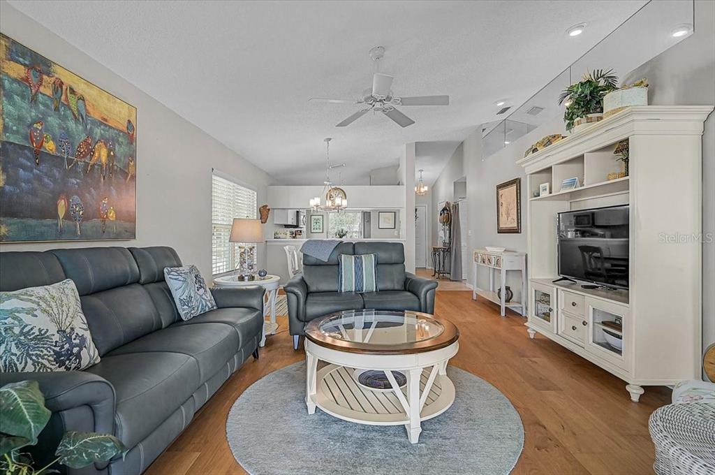 A living room features a dark leather sofa, a round coffee table, and a white entertainment center — 4219 CADDIE DRIVE E UNIT 204, BRADENTON, FL
