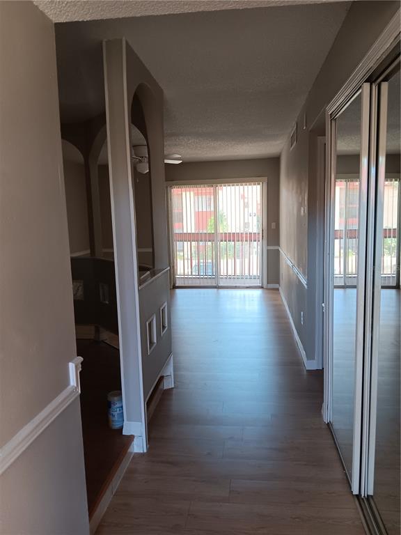A hallway with wood-look flooring leads to a living area with sliding glass balcony doors — 2860 N POWERS DRIVE UNIT 8, ORLANDO, FL