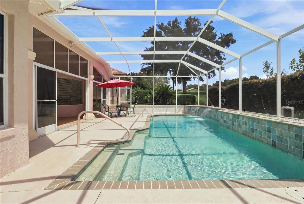 A screened-in patio features a swimming pool with water features and a dining area — 1821 N GIBSON POINT, HERNANDO, FL
