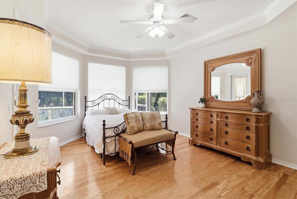 A bedroom features a metal bed frame, wooden dresser with mirror, and hardwood flooring — 1821 N GIBSON POINT, HERNANDO, FL