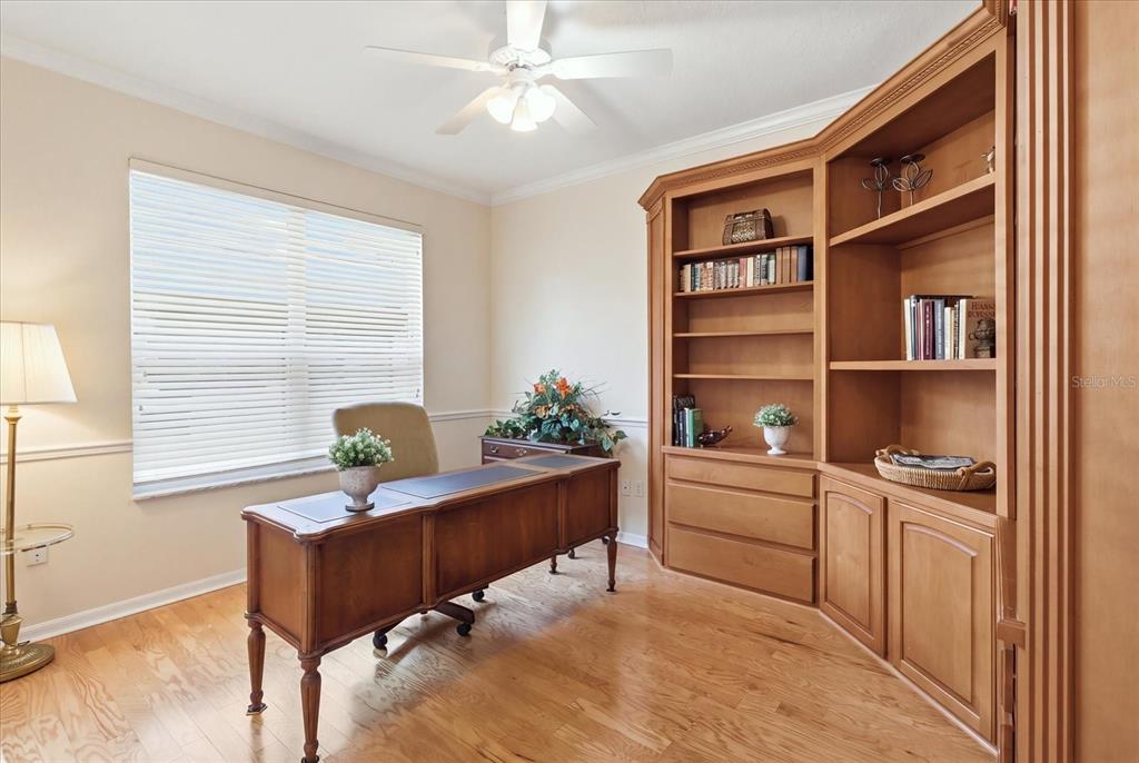 A home office features a wooden desk, built-in shelving, and hardwood flooring — 1821 N GIBSON POINT, HERNANDO, FL