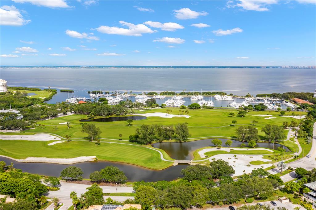 An aerial view shows a golf course with ponds and a marina on the water — 2600 HARBOURSIDE DRIVE UNIT C13, LONGBOAT KEY, FL