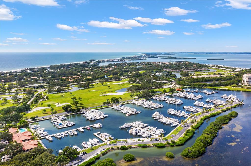 An aerial view shows a marina filled with boats adjacent to a golf course — 2600 HARBOURSIDE DRIVE UNIT C13, LONGBOAT KEY, FL