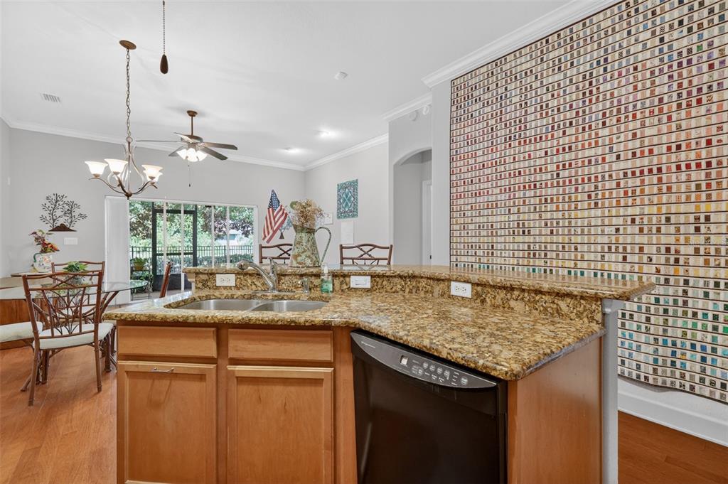 A kitchen features light wood cabinets, granite countertops, a breakfast bar, and hardwood flooring — 1010 GREEN GATE BOULEVARD, GROVELAND, FL